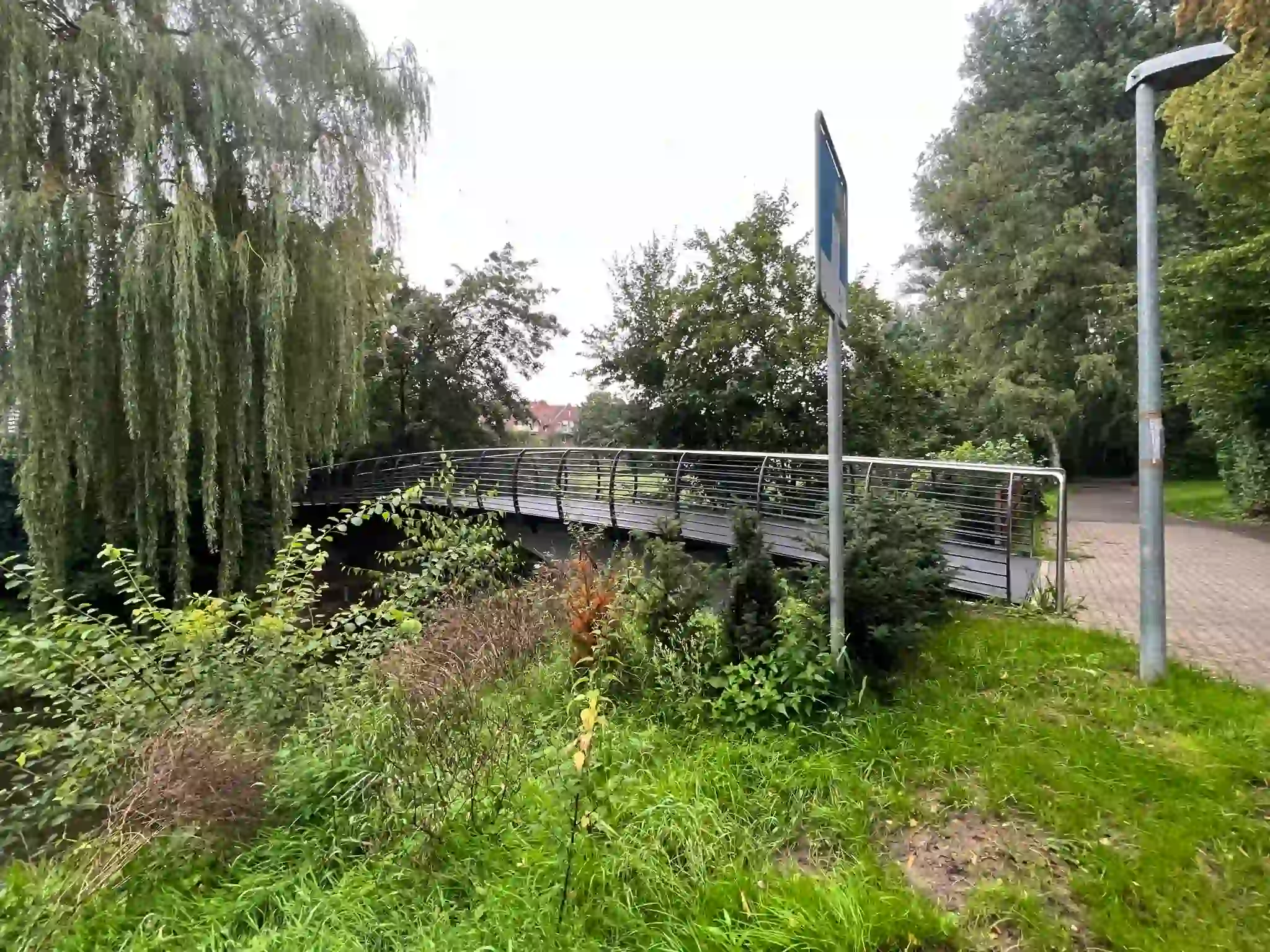 Brücke Kolpingweg über die Bastau in Minden 2023. Fotografie zeigt die Brücke fast vollständig von der linken Seite aus aufgenommen und aus etwas weiterer Entfernung.